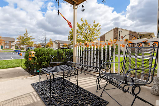 A black metal bench with a black metal table in front of a house.
