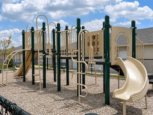A playground with a slide, monkey bars, and a climbing wall.