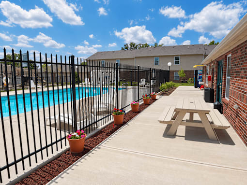 A black fence surrounds a pool and picnic table.