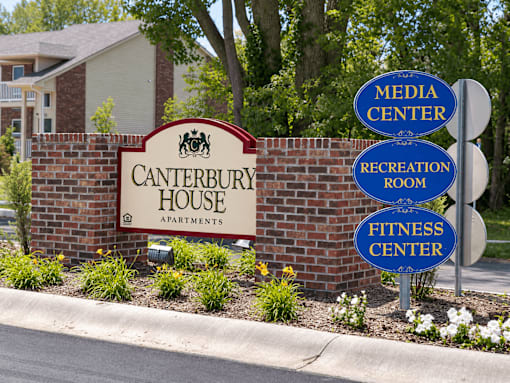 A sign for Canterbury House Apartments with three directional signs for Media Center, Recreation Room, and Fitness Center.