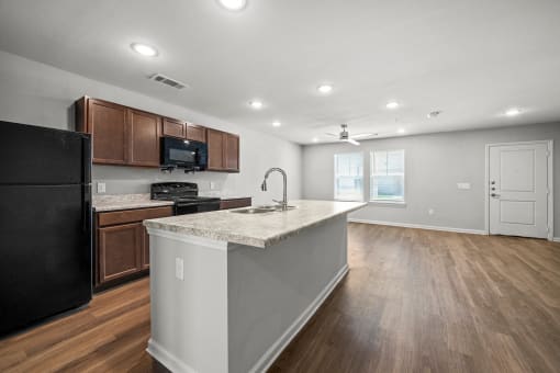 a kitchen with a large island and a black refrigerator