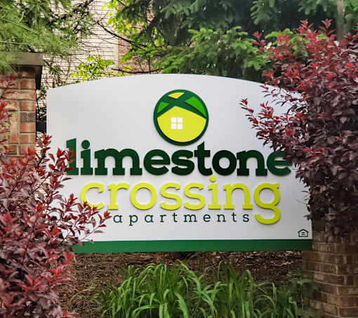 A sign for Limestone Crossing Apartments is displayed in front of some plants.