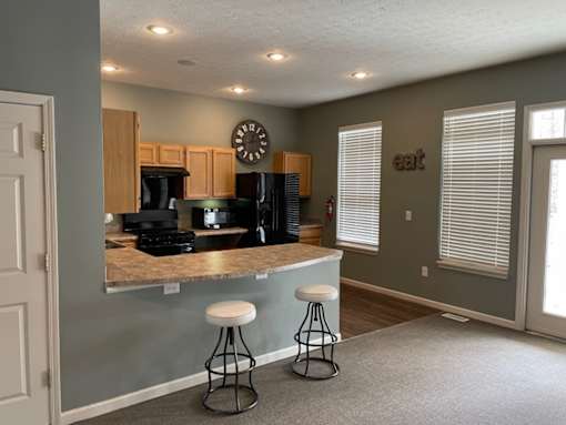 A kitchen with a bar stool in front of a counter.