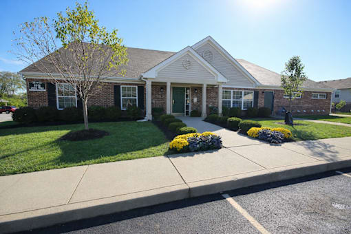 A house with a green lawn and a tree in front.