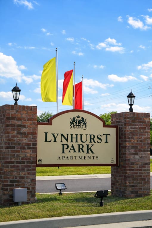 A sign for Lynhurst Park Apartments with flags on top.