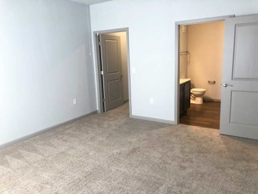 Empty bedroom with a bathroom in the background at Mosaic Apartments in Avon, Indiana