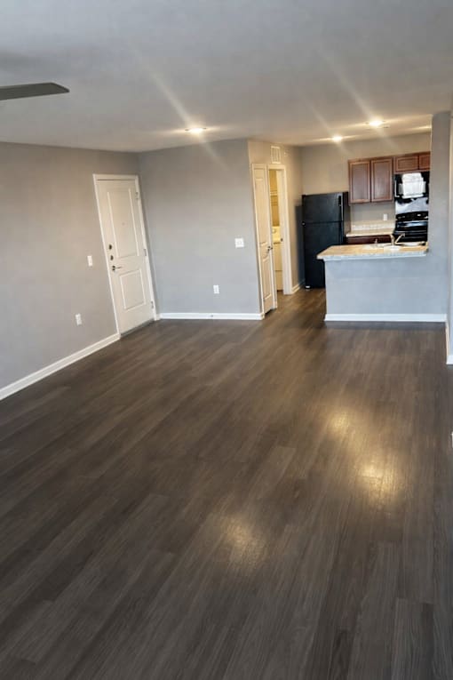 A kitchen with a refrigerator and cabinets is visible through an open door.