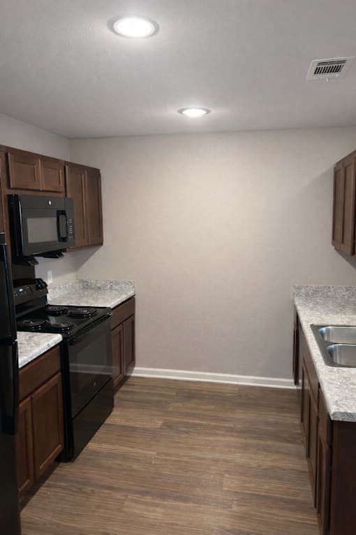 A kitchen with a black stove top oven and microwave.