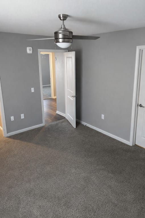 A room with a ceiling fan and carpeted floor.