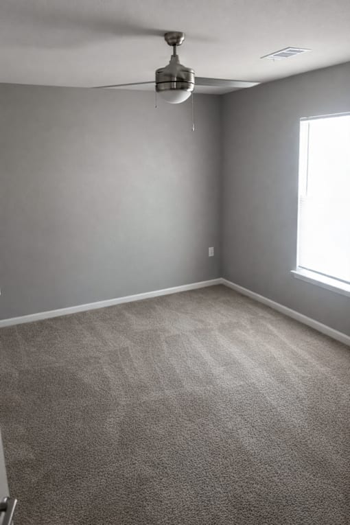 A room with a ceiling fan and a window.
