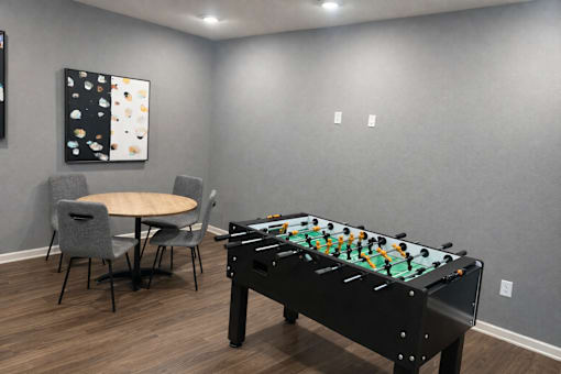 A pool table is in the middle of a room with a table and chairs.