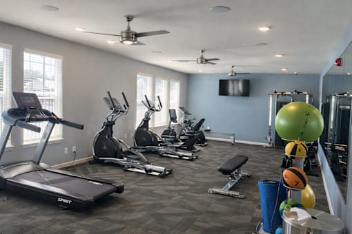 A gym with a variety of equipment including treadmills, exercise bikes, and weightlifting equipment.