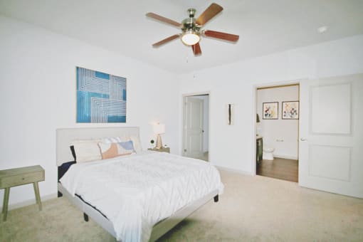 a bedroom with a large white bed and a ceiling fan