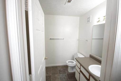 A white bathroom with a toilet, sink, and mirror.