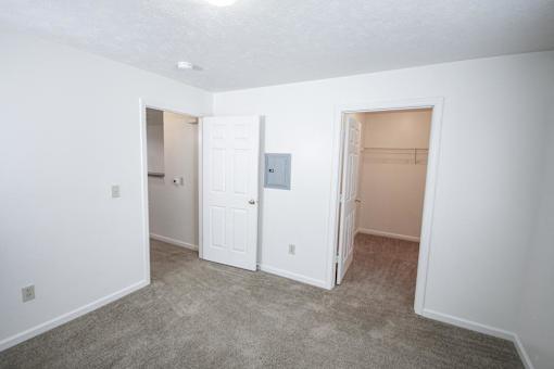 A room with a carpeted floor and three doors.