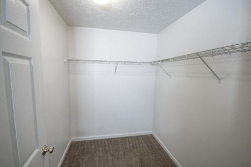 A white room with a door and a shelf.