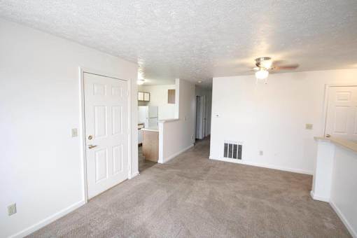 A spacious room with a carpeted floor and a ceiling fan.