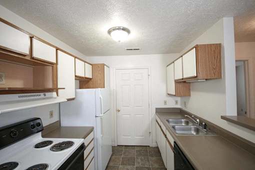 A kitchen with a white door and a stove top oven.