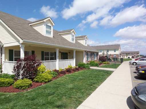 A row of houses with white fences and green bushes in front.