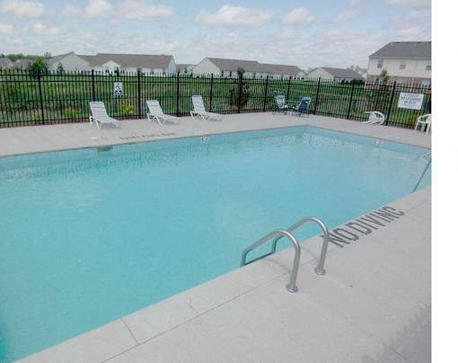 A pool with a ladder and chairs around it.