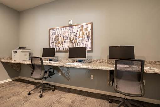 a desk with three computer monitors and a printer on top of it