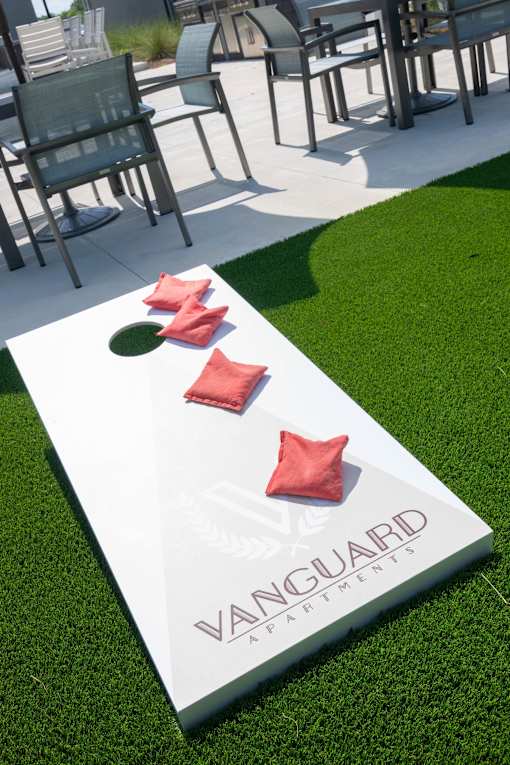 A white Vanguard branded cornhole board with red bags laying across it