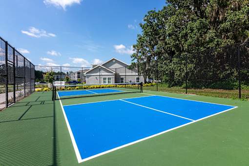 A tennis court with a green and blue surface surrounded by a fence.