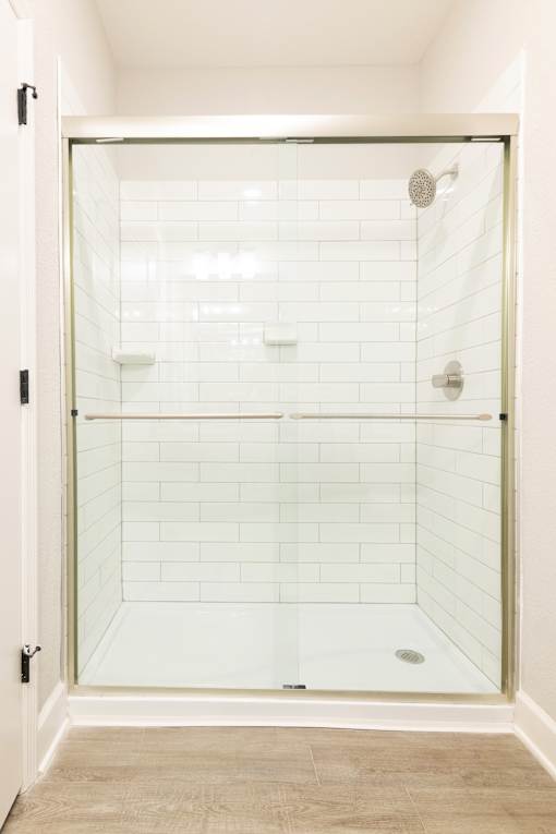 A white tiled shower with a glass door.