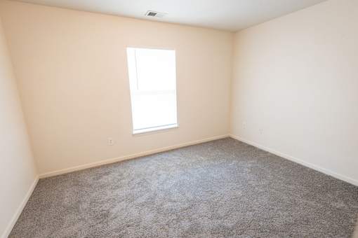 A room with a carpeted floor and a window.