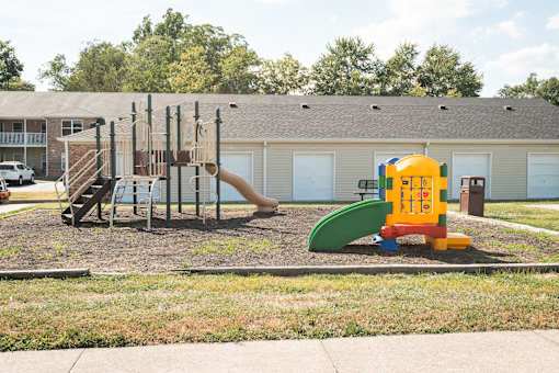 A playground with a yellow and green slide and a red and blue climbing frame.
