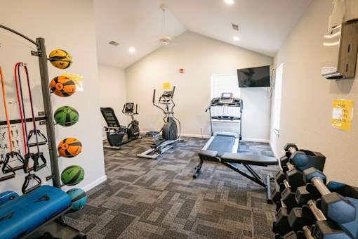A gym with a variety of equipment including a treadmill, weights, and resistance bands.