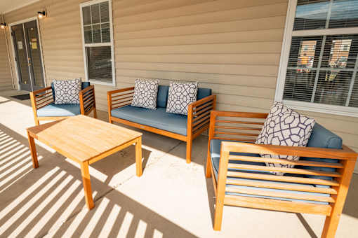 A wooden chair and table are on a patio.