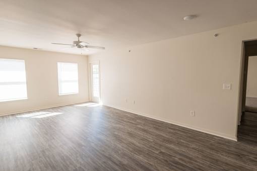 A room with a ceiling fan and two windows.