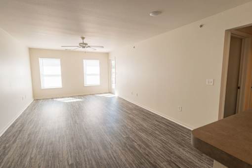 A room with a ceiling fan and two windows.