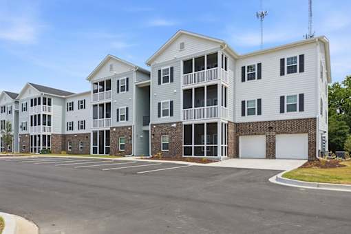 A large white apartment building with a parking lot in front.