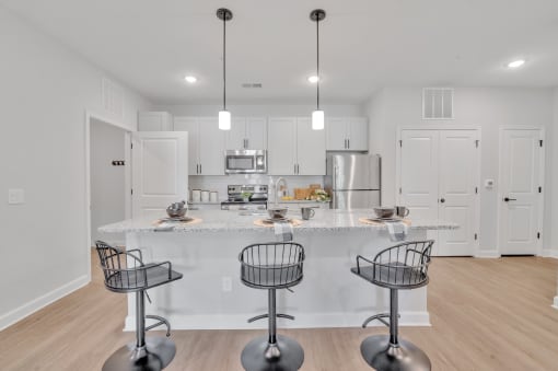 a kitchen with an island and bar stools in front of a kitchen counter top