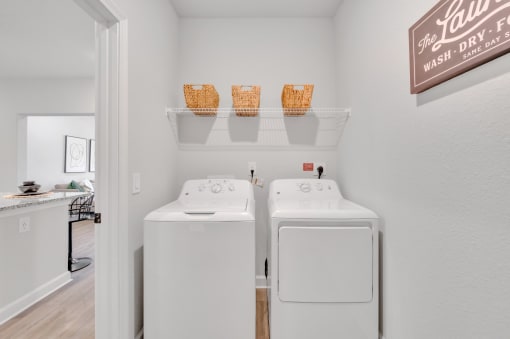 two washers and dryers in a laundry room with a door to a kitchen