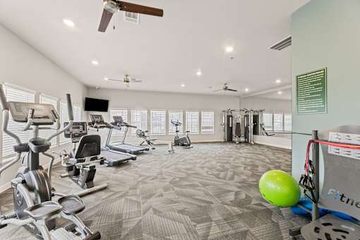 A gym with a variety of equipment including treadmills, weights, and exercise machines.