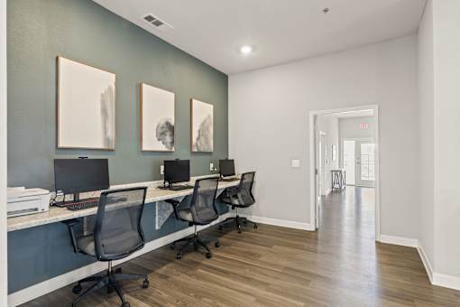 A room with a long desk and chairs and three pictures on the wall.