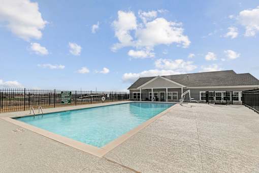 A large outdoor swimming pool with a black fence surrounding it.