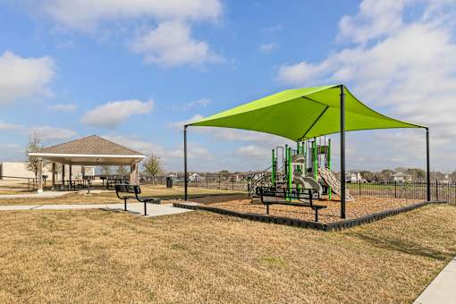 A playground with a green canopy and a slide.