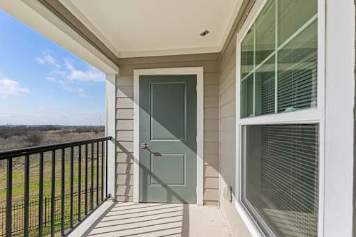 A balcony with a green door and a black railing.