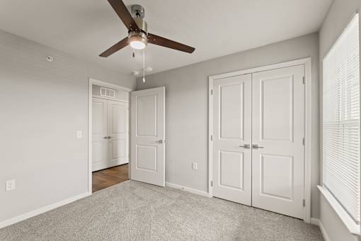 A room with a ceiling fan and two doors.