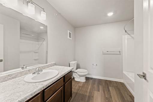 A white bathroom with a sink, toilet, and a mirror.
