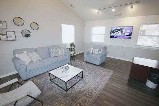 A living room with a grey couch, a white coffee table, and a television on the wall.
