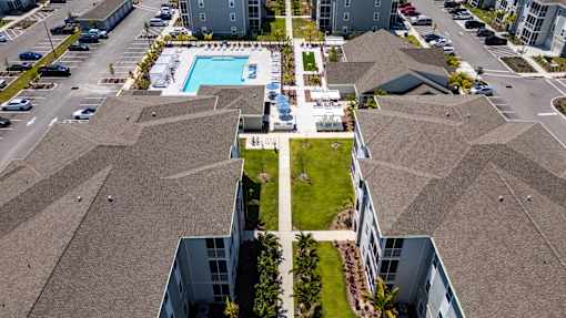A bird's eye view of a residential area with houses, cars, and a swimming pool.