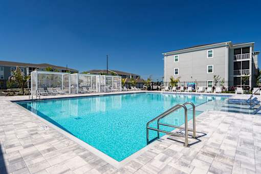 A large swimming pool surrounded by a tiled floor and a metal ladder.