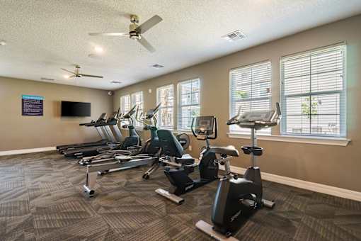 A gym with treadmills, exercise bikes, and a television.
