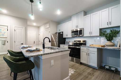 A kitchen with a table set for two and a green chair.