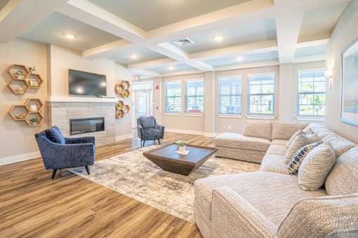 Clubhouse lounge area with a coffee table, tv and chairs at Trillium Luxury apartments in melbourne fl